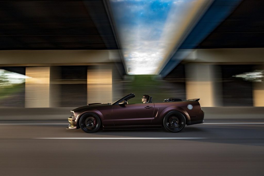 a muscle car is passing the arch of the bridge