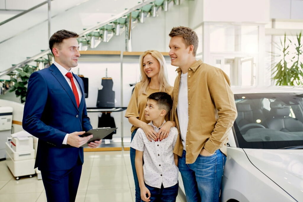 car dealer discussing vehicle purchase with a family in a dealership showroom